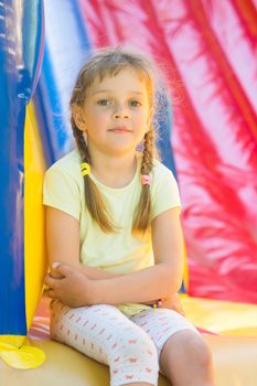 Five-year girl naprygalis on a large inflatable trampoline sat down to rest
