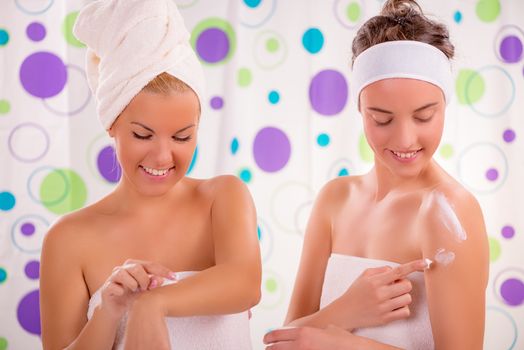 Two young cute woman applying body lotion and get ready to start their day.