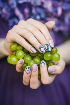 Beautiful hands with wonderful nails Holding a Bunch of Green Grapes