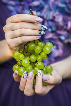Beautiful hands with wonderful nails Holding a Bunch of Green Grapes