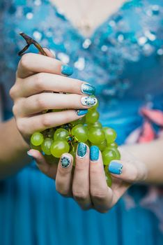 Beautiful hands with wonderful nails Holding a Bunch of Green Grapes