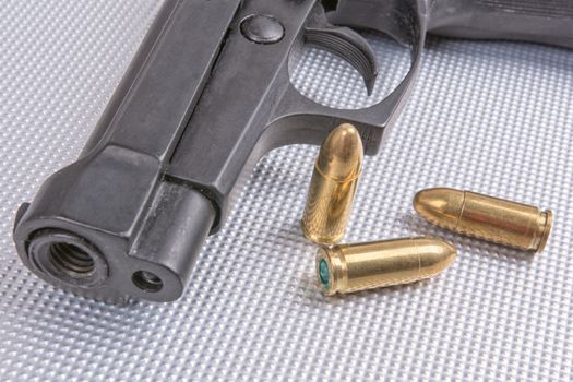Gold bullets and gun on aluminium background