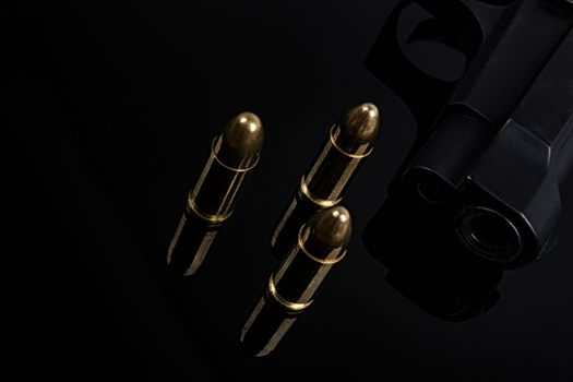 Gold bullets and gun on black background