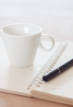 Pen and spiral notebook with coffee cup, stock photo