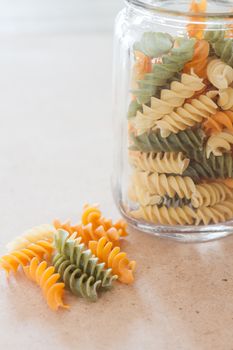 Raw fusilli pasta with glass bottle, stock photo