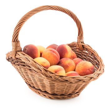 Basket full of fresh peaches isolated on white background. Selective focus.