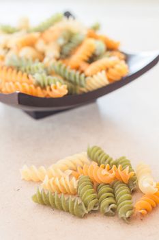 Raw fusilli pasta on wooden tray, stock photo