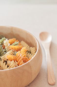 Raw fusilli pasta on wooden bowl, stock photo