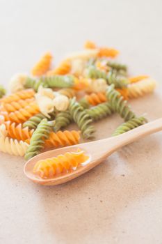 Raw fusilli pasta with wooden spoon, stock photo