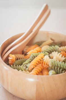 Raw fusilli pasta on wooden bowl, stock photo