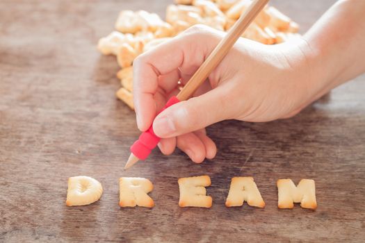 Dream alphabet biscuit on wooden table, stock photo