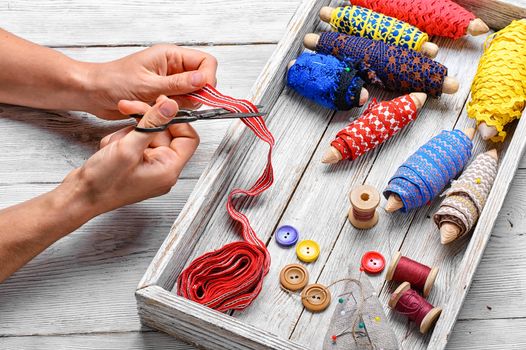 hands of tailor sewing accessories on background thread and buttons