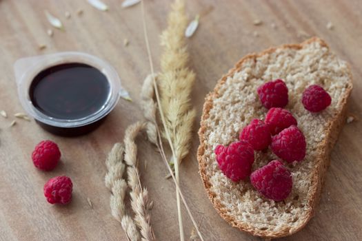 bread raspberries jam and ears on wooden table