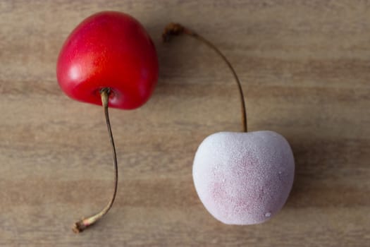 two cherries: one frozen and one fresh