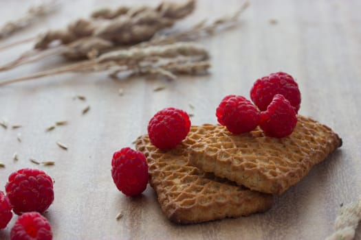 cookies with raspberries and ears on wooden table