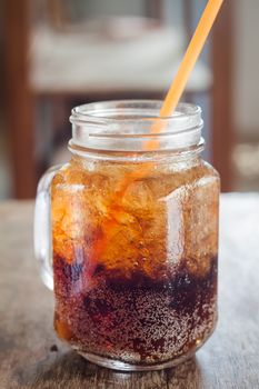 Glass of cola with ice on wooden table, stock photo