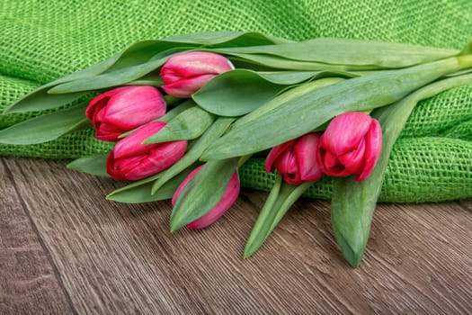 Red tulips on a brown wooden background