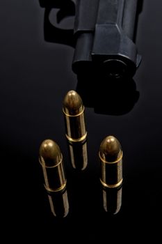 Gold bullets and gun on black background