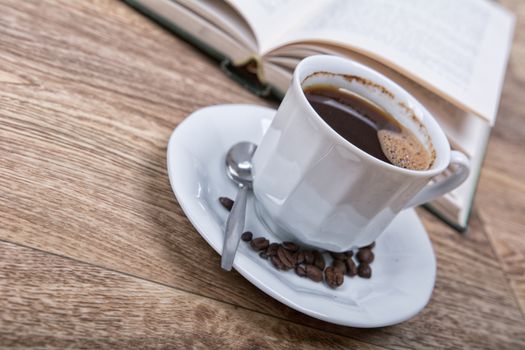 A cup of coffee with a book on a wooden background