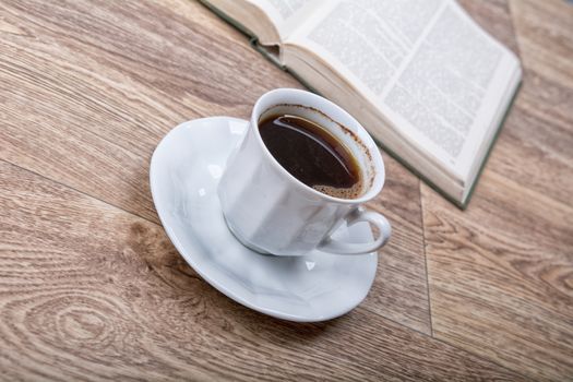 A cup of coffee with a book on a wooden background