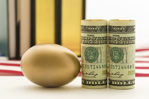 Gold nest egg next to American currency with books in background. 