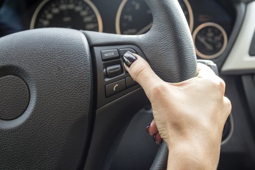 Arm girls with trendy manicure holds the steering wheel in the car.