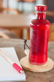 Red syrup in the bottle on wooden plate, stock photo