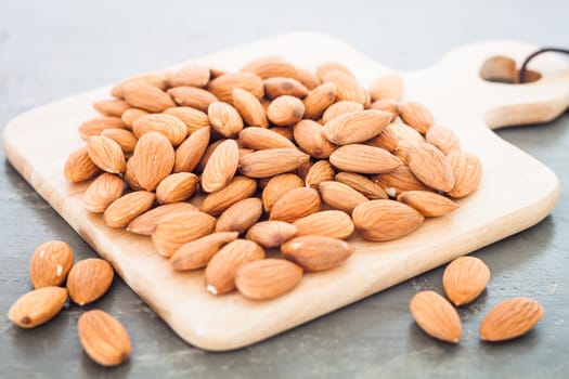 Almond nuts on wooden plate, stock photo