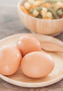 Fresh eggs on wooden plate with fusili , stock photo