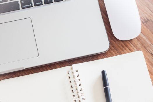 Notepad and laptop on wood table, stock photo