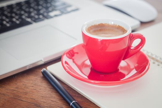 Red coffee cup with notepad and laptop, stock photo
