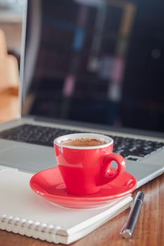Red coffee cup with notepad and laptop, stock photo