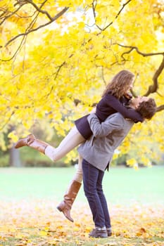 Smiling couple hugging in autumn park with yellow trees