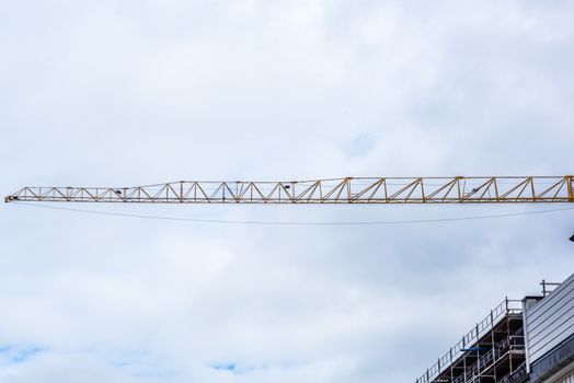 The top of a tower crane sticking out from a building. With copy space above and below.