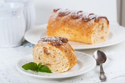 Biscuit roll with condensed milk on a table, selective focus