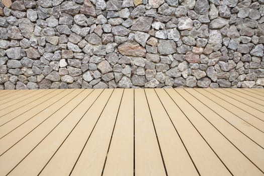 Wood floor boards with a stone wall background
