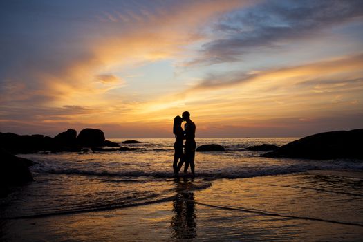 Couple kissing on the beach with a beautiful sunset in background