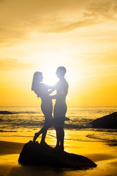 Couple kissing on the beach with a beautiful sunset in background