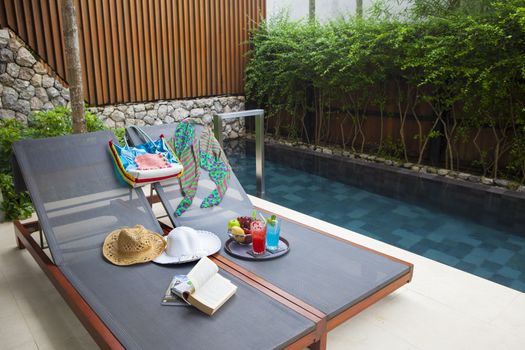 Reclining chair with bag, hat, bag, book, nectar and fruit eat when resting.