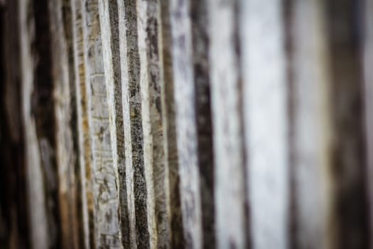 Detail view along an old  picket wooden fence with selective focus