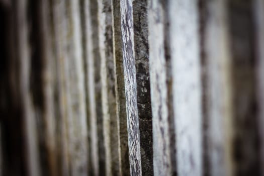 Detail view along an old  picket wooden fence with selective focus