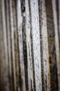 Detail view along an old  picket wooden fence with selective focus