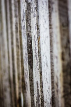 Detail view along an old  picket wooden fence with selective focus