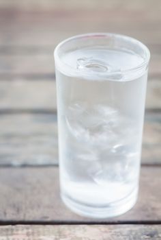 Glass of iced water on wooden table, stock photo