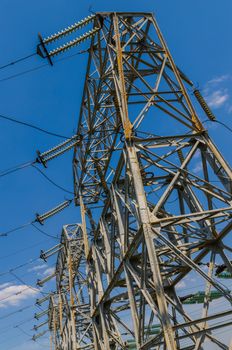 supports of high-voltage power lines against the blue sky