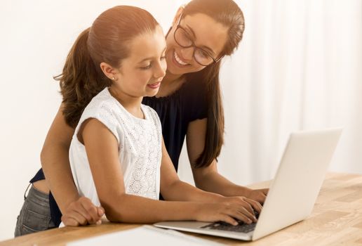 Mother helping her little daughter how to use a computer