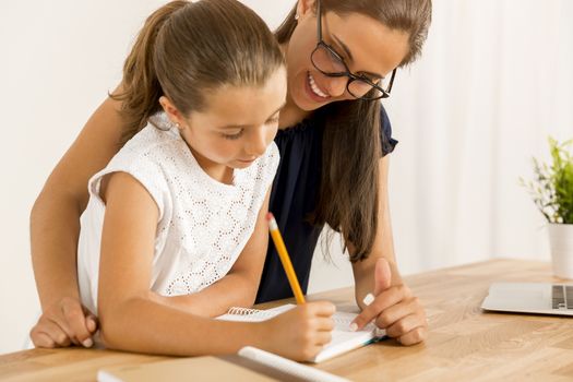 Mother and daugther at home doing homework together