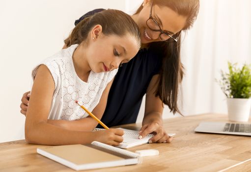 Mother and daugther at home doing homework together