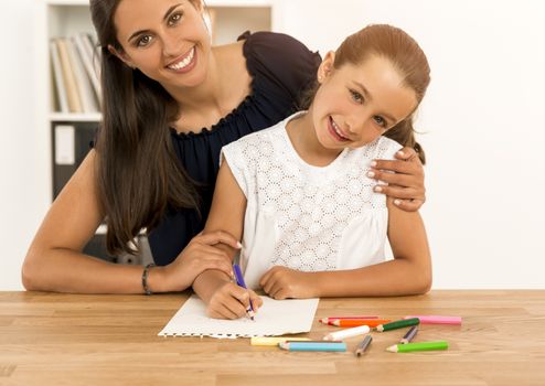 Mother helping her little daughter making drawings