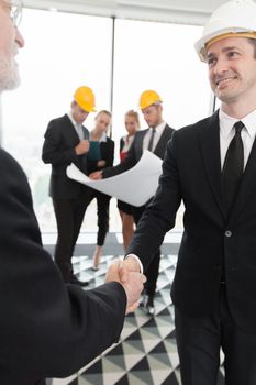 Handshake of architect and investor, business team with blueprint on background